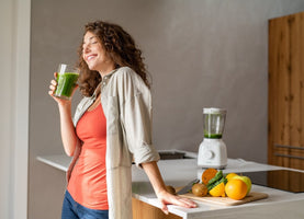 Woman drinking a green smoothie as part of a healthy post holiday detox routine